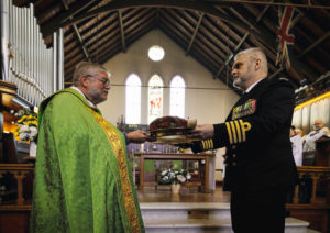 Commanding Officer of HMAS Kuttabul Captain Viktor Pilicic, CSC, RAN (right) receives the perished Australian White Ensign from the parish of St John's church, Birchgrove, New South Wales.