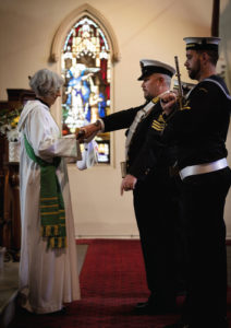 Royal Australian Navy Chaplain Catherine Wynn-Jones receives the replacement Australian White Ensign on behalf of St John's church, Birchgrove, New South Wales.