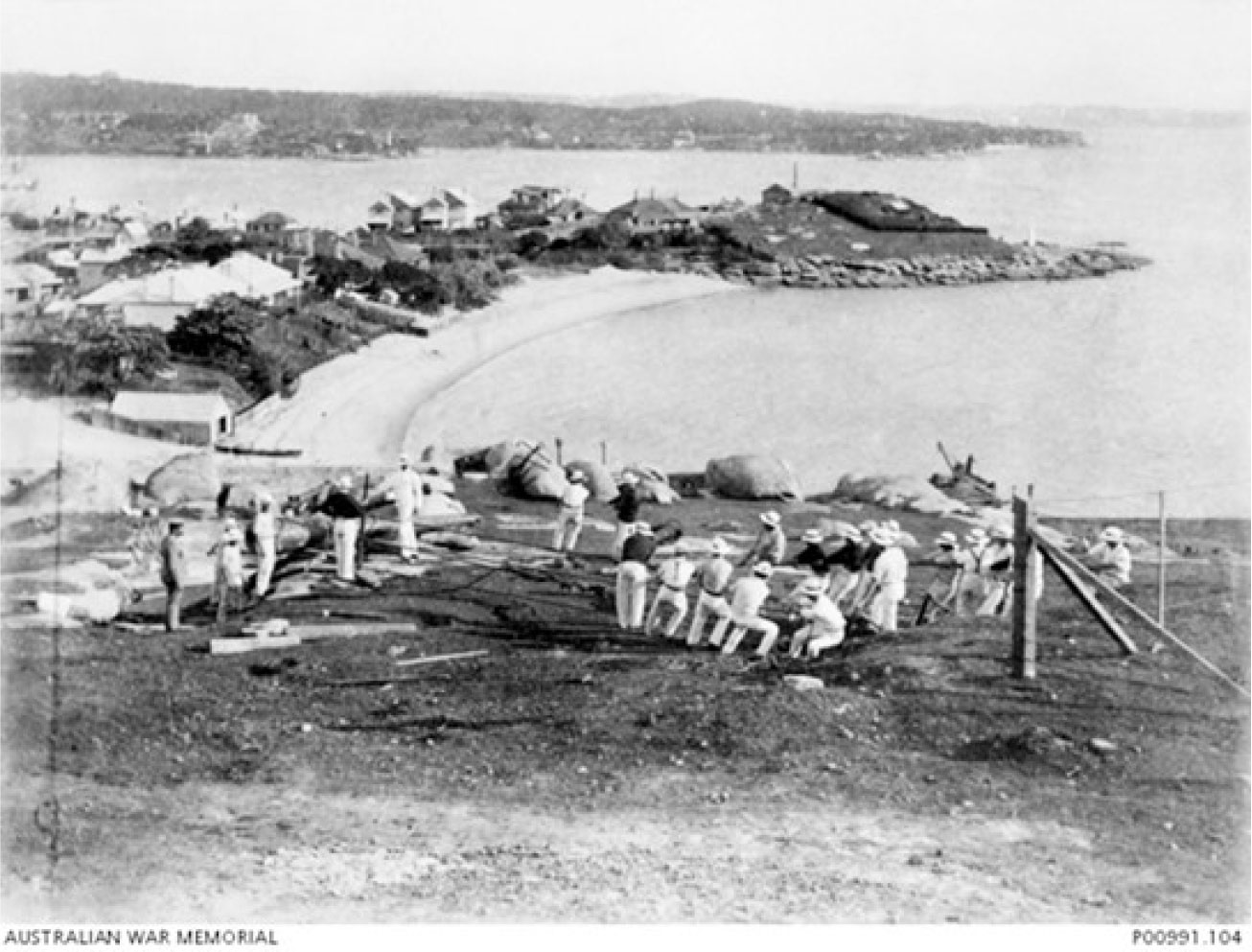 1910. Members of the Short Course (1910-04-24 to 1910-07-23) at the South Head Commonwealth Gunnery School using brute strength to move a 6 inch, Mark 5 gun barrel on a slope. Green Point is in the background. (Donor Royal Australian Artillery Historical Society)